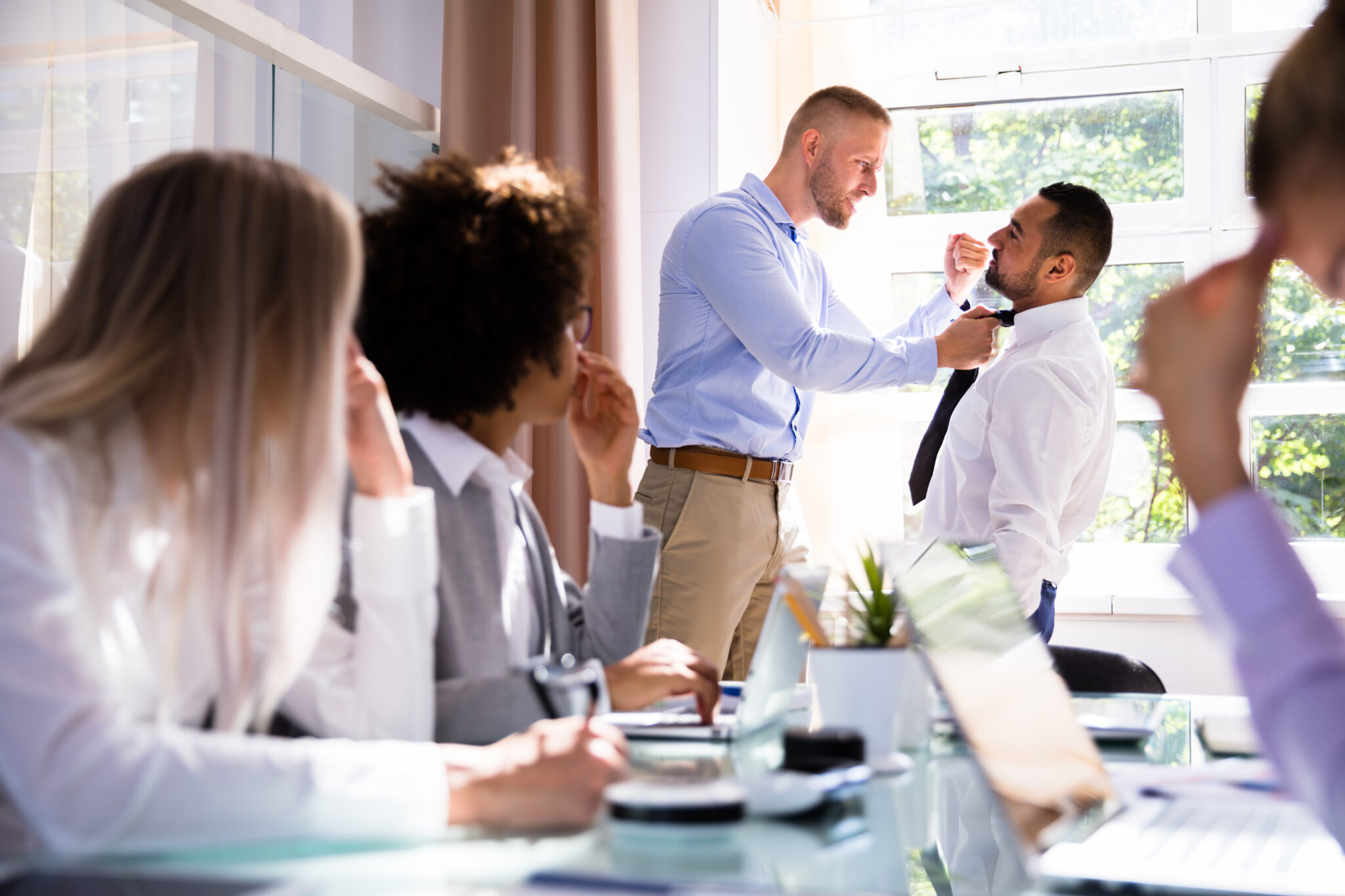 Stressed Businesspeople Sitting In Front Of Two Colleagues Fighting In Office